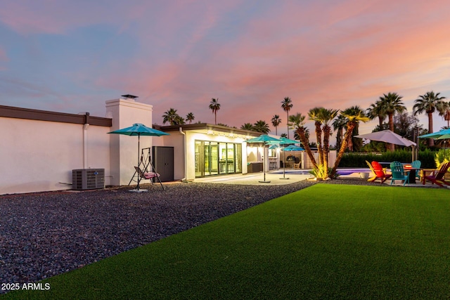 675 Val Verde Cir W, Litchfield Park, AZ 85340 - rear view of house featuring a patio, stucco siding, central AC, a lawn, and a chimney