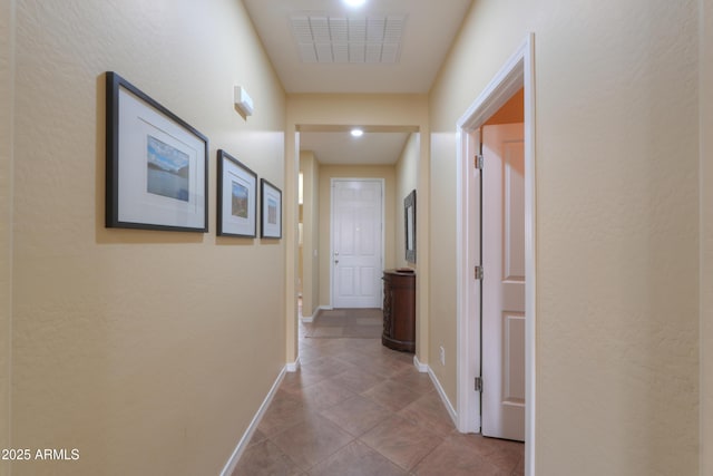 corridor featuring visible vents, baseboards, and tile patterned floors