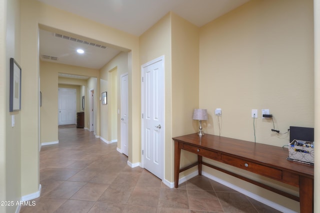 corridor with baseboards, visible vents, and tile patterned flooring