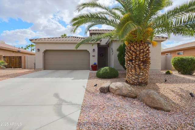 mediterranean / spanish-style house with an attached garage, concrete driveway, a tiled roof, a gate, and stucco siding