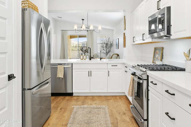 kitchen featuring white cabinetry, light hardwood / wood-style flooring, lofted ceiling, and stainless steel appliances