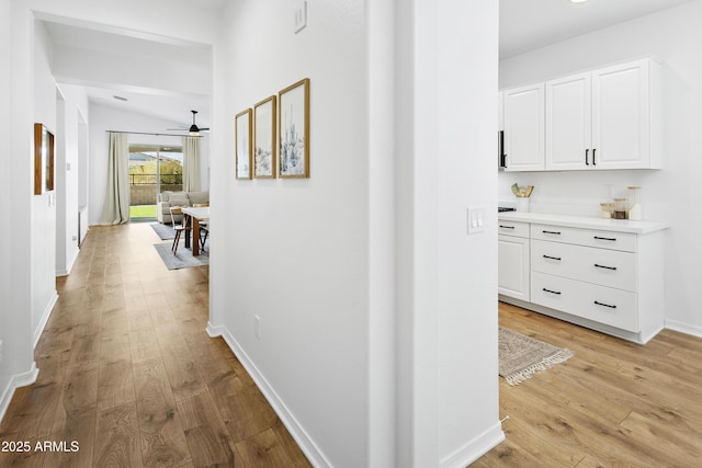 hallway with light hardwood / wood-style floors and lofted ceiling