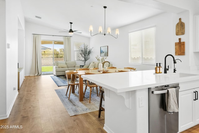 kitchen featuring stainless steel dishwasher, pendant lighting, sink, white cabinetry, and lofted ceiling