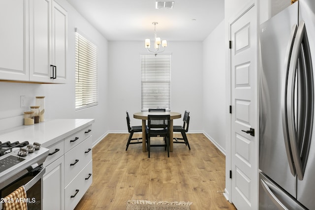 dining space with light wood-type flooring and an inviting chandelier