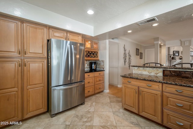 2125 E Elmwood St, Mesa, AZ 85213 - kitchen featuring freestanding refrigerator, brown cabinetry, decorative backsplash, dark stone counters, and ornamental molding