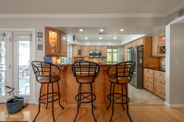 2125 E Elmwood St, Mesa, AZ 85213 - kitchen with appliances with stainless steel finishes, a peninsula, crown molding, a kitchen bar, and tasteful backsplash