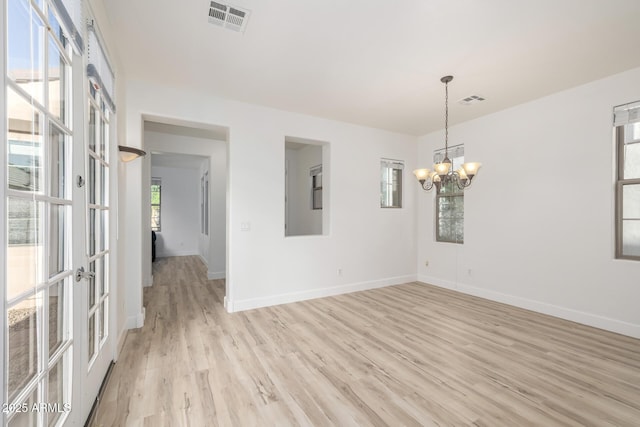 15469 W Dreyfus St, Surprise, AZ 85379 - empty room featuring light wood-style flooring, baseboards, a chandelier, and french doors