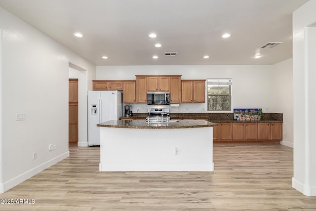 15469 W Dreyfus St, Surprise, AZ 85379 - kitchen with appliances with stainless steel finishes, brown cabinetry, light wood-style floors, a kitchen island with sink, and recessed lighting