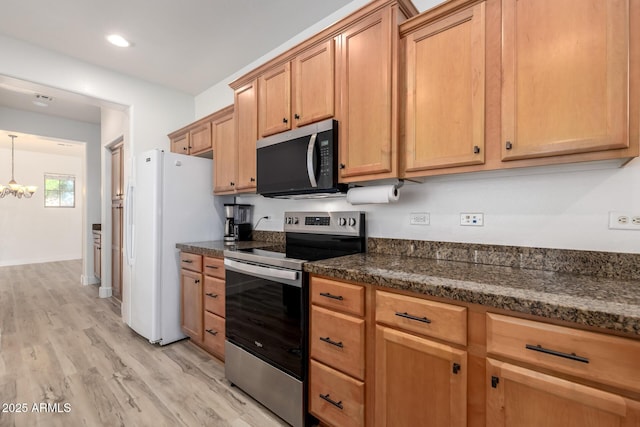 15469 W Dreyfus St, Surprise, AZ 85379 - kitchen with stainless steel appliances, light wood-style floors, a chandelier, dark stone counters, and pendant lighting