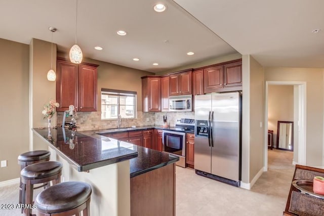 kitchen with sink, dark stone countertops, hanging light fixtures, stainless steel appliances, and kitchen peninsula