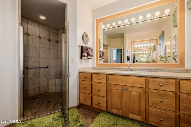 bathroom with tile patterned flooring, a shower with shower door, and vanity