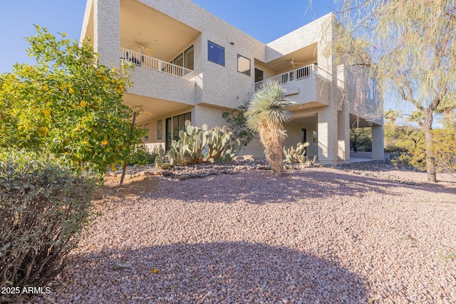 rear view of property with a balcony and ceiling fan