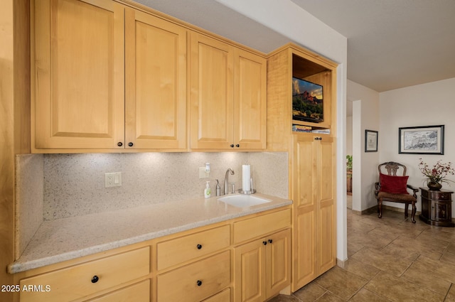 kitchen with light brown cabinetry, decorative backsplash, sink, and light stone counters