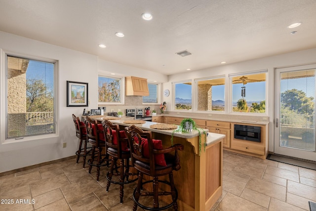 kitchen featuring a healthy amount of sunlight, kitchen peninsula, black microwave, and a breakfast bar area