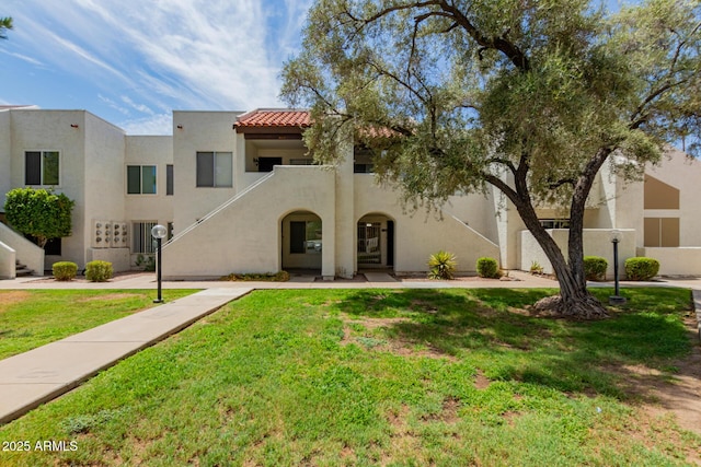 view of front of property with a tiled roof, a front lawn, and stucco siding