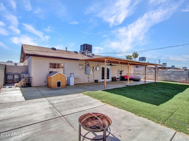 back of property with a patio, ceiling fan, central AC, an outdoor fire pit, and a yard