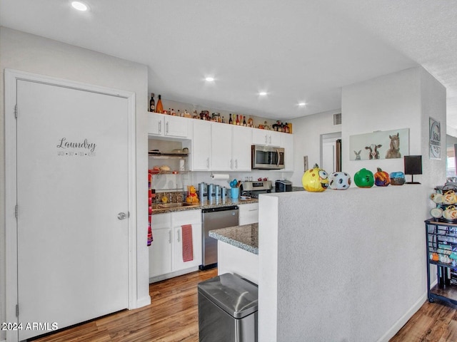 kitchen featuring white cabinetry, sink, dark stone countertops, appliances with stainless steel finishes, and light wood-type flooring