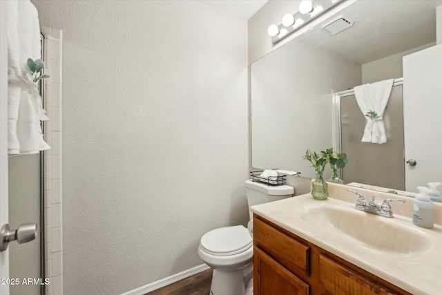 bathroom with a shower with door, baseboards, toilet, wood finished floors, and vanity