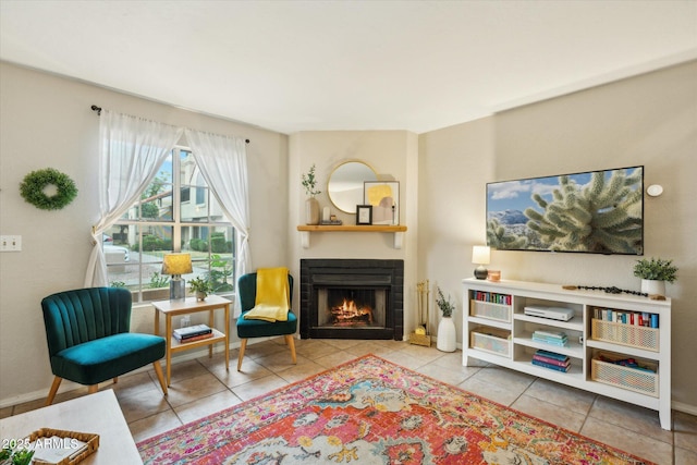 sitting room with baseboards, a fireplace with flush hearth, and tile patterned flooring