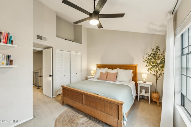 bedroom featuring visible vents, ceiling fan, light carpet, a closet, and high vaulted ceiling