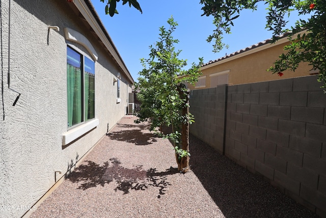 view of side of property featuring stucco siding and fence