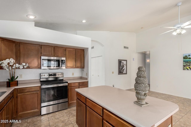 626 W Catclaw St, Gilbert, AZ 85233 - kitchen featuring brown cabinetry, lofted ceiling, ceiling fan, light countertops, and appliances with stainless steel finishes