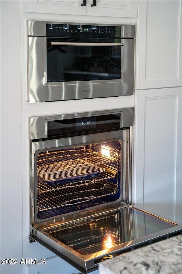 details featuring stainless steel oven, white cabinets, and wine cooler