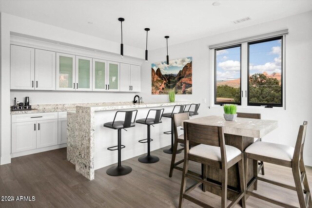 kitchen with pendant lighting, a breakfast bar area, dark wood-type flooring, and white cabinets