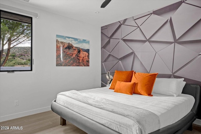 bedroom featuring ceiling fan, light wood-type flooring, and multiple windows