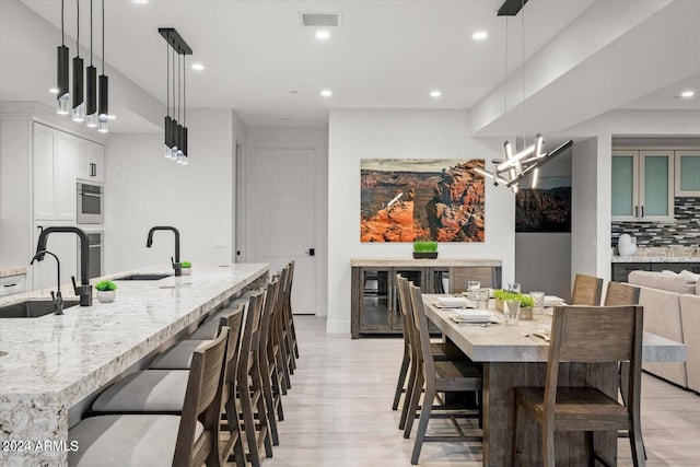 kitchen featuring tasteful backsplash, sink, a large island, a kitchen bar, and decorative light fixtures