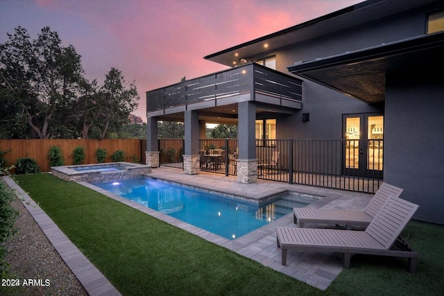 pool at dusk with a yard, an in ground hot tub, and a patio