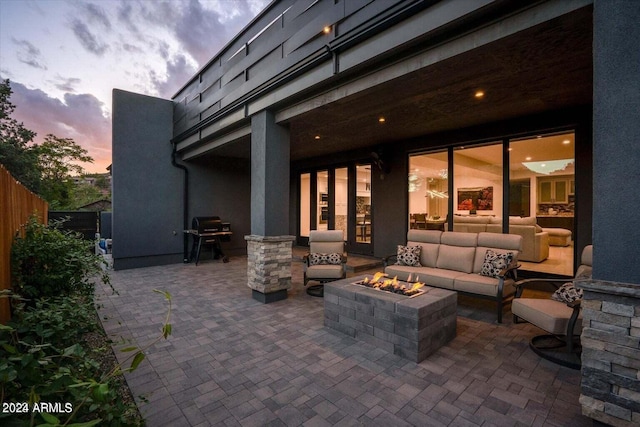 patio terrace at dusk with an outdoor living space with a fire pit and a grill