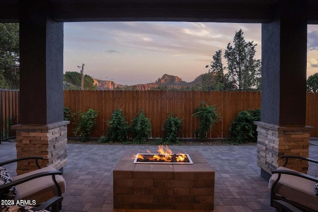 patio terrace at dusk featuring a mountain view and an outdoor fire pit