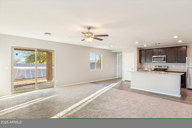431 W Guinea Ct, Casa Grande, AZ 85122 - kitchen with stainless steel appliances, recessed lighting, light countertops, dark brown cabinetry, and an island with sink