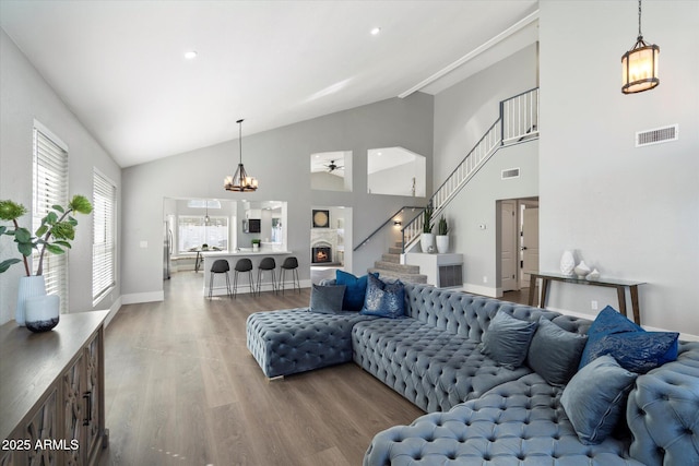 living room with visible vents, a fireplace, stairway, and wood finished floors