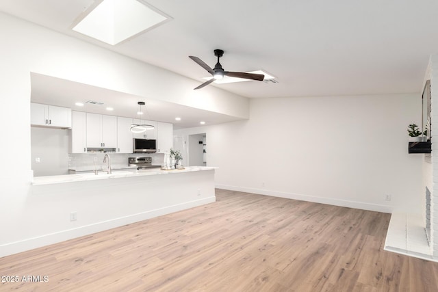 4310 E Sacaton St, Phoenix, AZ 85044 - unfurnished living room featuring a sink, baseboards, a ceiling fan, light wood-style flooring, and a skylight
