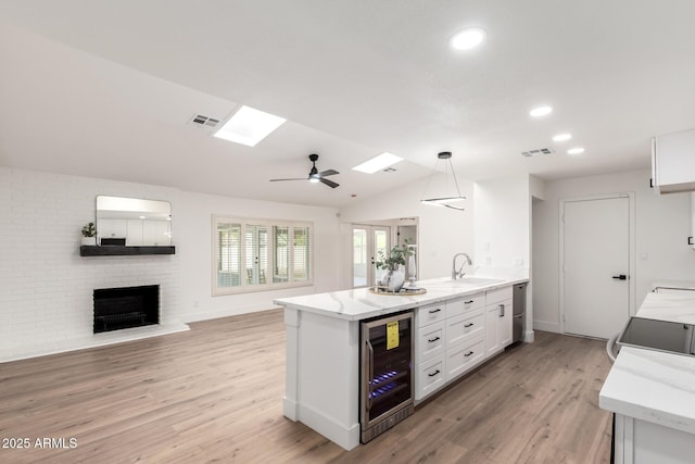 4310 E Sacaton St, Phoenix, AZ 85044 - kitchen featuring white cabinets, a brick fireplace, open floor plan, wine cooler, and visible vents