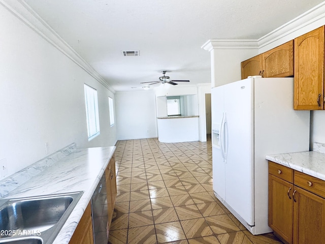 kitchen featuring a sink, white refrigerator with ice dispenser, a ceiling fan, brown cabinetry, and crown molding