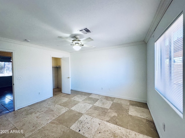 unfurnished bedroom featuring ornamental molding, baseboards, light stone finish flooring, ceiling fan, and a closet