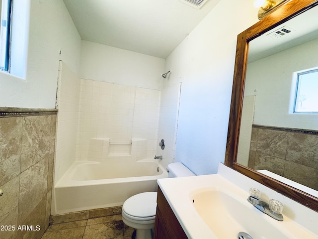 full bathroom featuring tile walls, toilet, vanity, tile patterned floors, and tub / shower combination