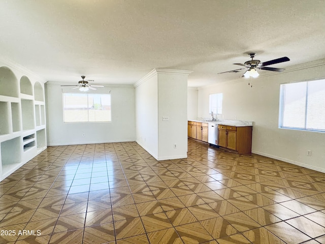 unfurnished living room with ceiling fan, crown molding, a sink, baseboards, and built in shelves