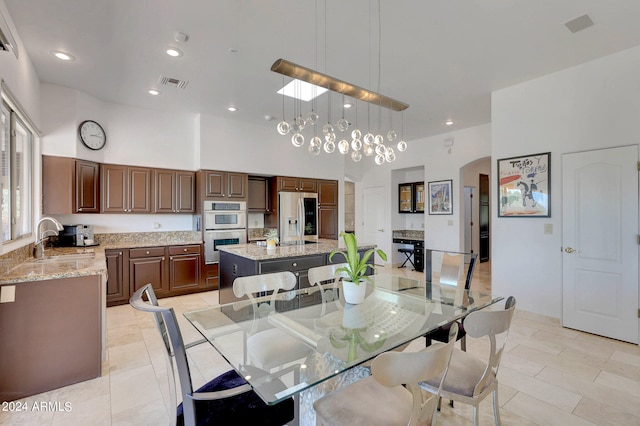 dining space featuring light tile patterned flooring, a towering ceiling, and sink