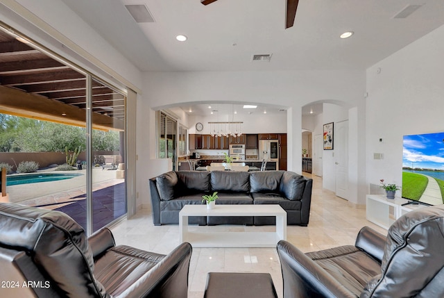 tiled living room with ceiling fan with notable chandelier and a wealth of natural light