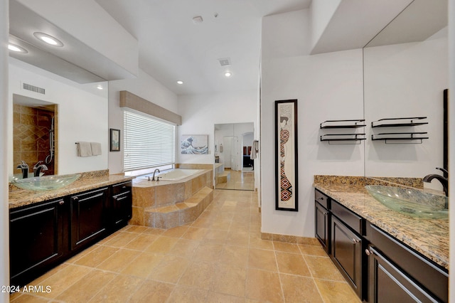 bathroom with tile patterned flooring, tiled bath, and vanity