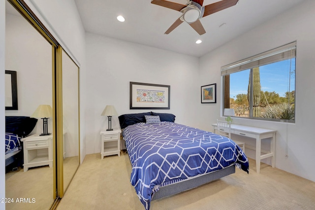 bedroom featuring light carpet, ceiling fan, and a closet