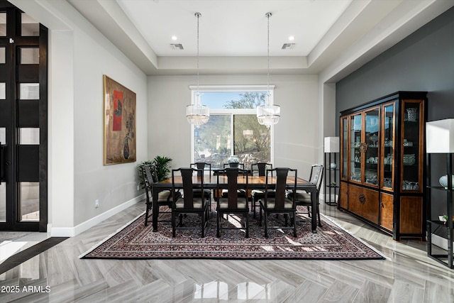 dining space featuring light parquet flooring, an inviting chandelier, and a tray ceiling