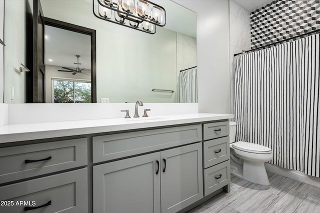 bathroom with toilet, walk in shower, vanity, and ceiling fan