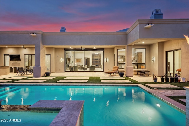 pool at dusk featuring a patio area and ceiling fan