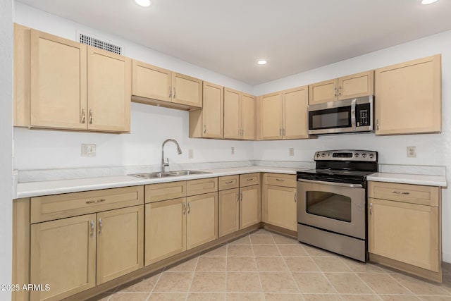 kitchen featuring light brown cabinets, sink, light tile patterned floors, and stainless steel appliances