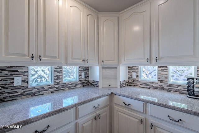 kitchen with white cabinets, light stone countertops, and backsplash